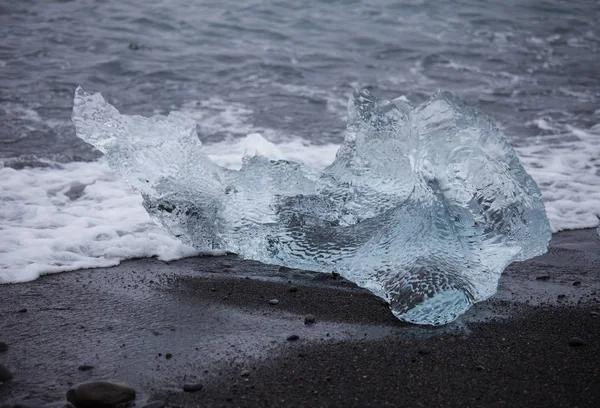 Amazing transparent blue iceberg pieces on Diamond beach with black sand near Jokulsarlon lagoon, Islândia. Parto de gelo. Exposição longa da água . — Fotografia de Stock