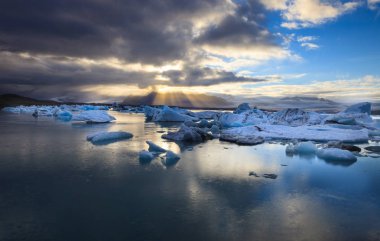 Dramatik bir günbatımı ayna su ile mavi buzdağı parçalar halinde Jokulsarlon lagün, İzlanda.
