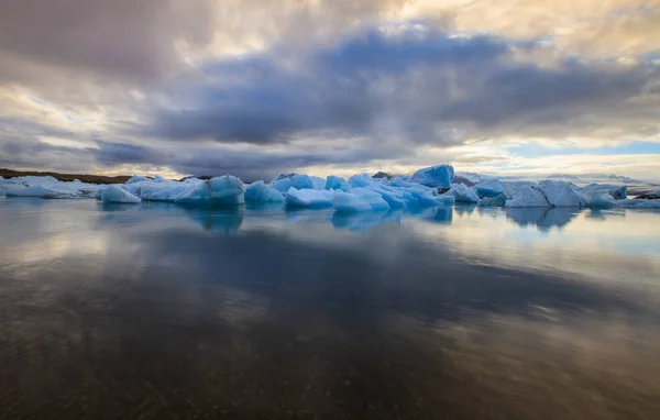 Dramatique un coucher de soleil avec de l'eau miroir avec des morceaux d'iceberg bleu dans la lagune de Jokulsarlon, Islande . — Photo