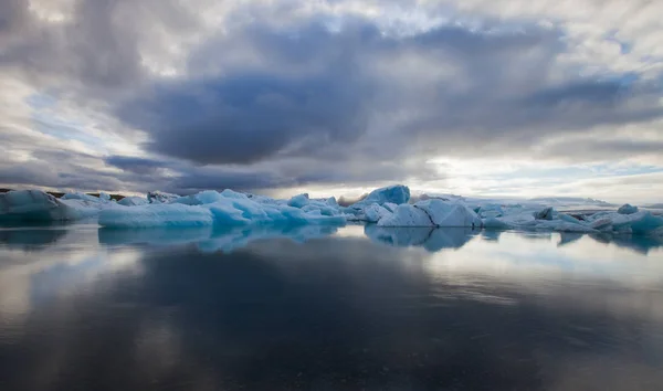 Dramatic een zonsondergang met spiegel water met blauwe ijsberg stukken in Jokulsarlon lagune, IJsland. — Stockfoto