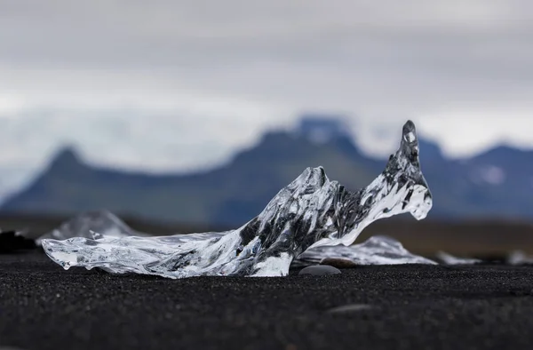アイスランドのヨクルサルロンラグーンの近くに黒い砂とダイヤモンドビーチで驚くほど透明な青い氷山の作品。氷の彫刻白黒コントラスト. — ストック写真