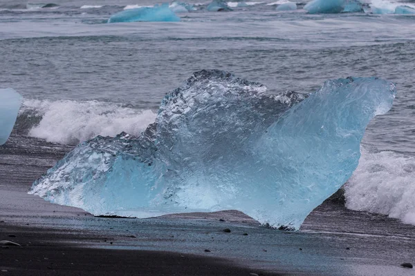 Csodálatos átlátszó kék jéghegy darabot a Diamond Beach fekete homok közelében Jokulsarlon lagúna, Izland. Jég ellés. Fekete-fehér kontraszt. — Stock Fotó