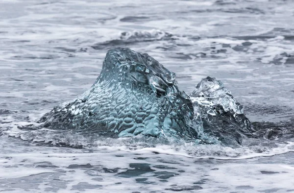 Incredibili pezzi di iceberg blu trasparente sulla spiaggia di Diamond con sabbia nera vicino alla laguna di Jokulsarlon, Islanda. Ghiaccio in arrivo. Contrasto bianco e nero . — Foto Stock