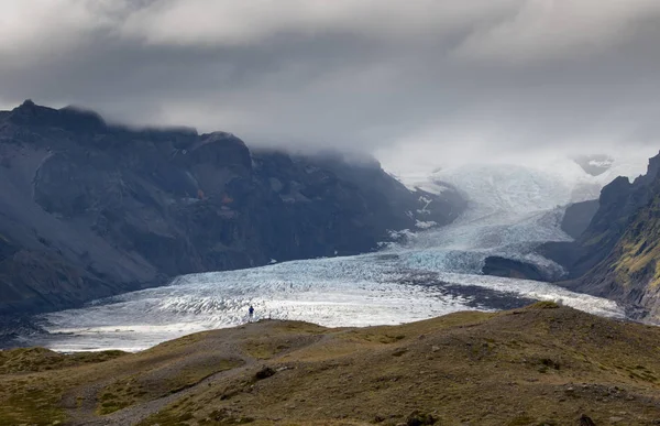 Langue du glacier en Islande dérivant de la montagne de mousse verte dans la journée brumeuse. La glace bleue du glacier est visible, ainsi que la mousse verte recouvrant les rochers de la montagne — Photo