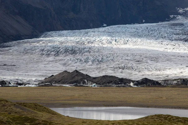 Langue du glacier en Islande dérivant de la montagne de mousse verte dans la journée brumeuse. La glace bleue du glacier est visible, ainsi que la mousse verte recouvrant les rochers de la montagne — Photo