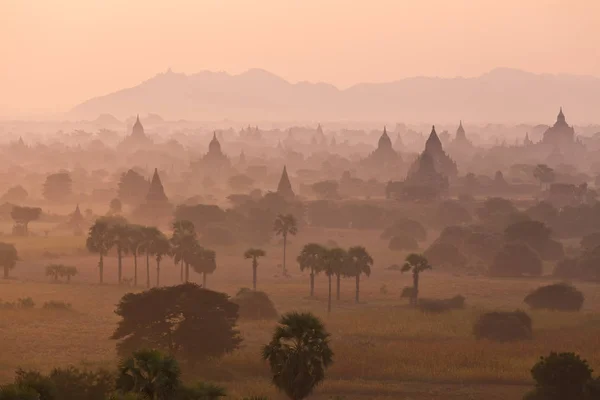 Vista mística laranja da paisagem do nascer do sol com silhuetas de antigos templos antigos e palmeiras no nevoeiro do amanhecer do balão, Bagan, Myanmar. Birmânia — Fotografia de Stock