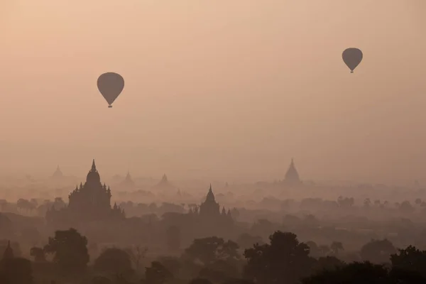 Orange mystischen Sonnenaufgang Landschaft Ansicht mit Silhouetten von alten antiken Tempeln und Palmen in der Morgendämmerung Nebel aus Ballon, Heiden, Myanmar. Burma — Stockfoto