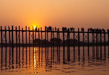 Gün batımında U Bein Köprüsü'nde siluetli insanlar, Amarapura, Mandalay bölgesi, Myanmar. Burma. Dünyanın en uzun ve en eski tik ahşap köprü