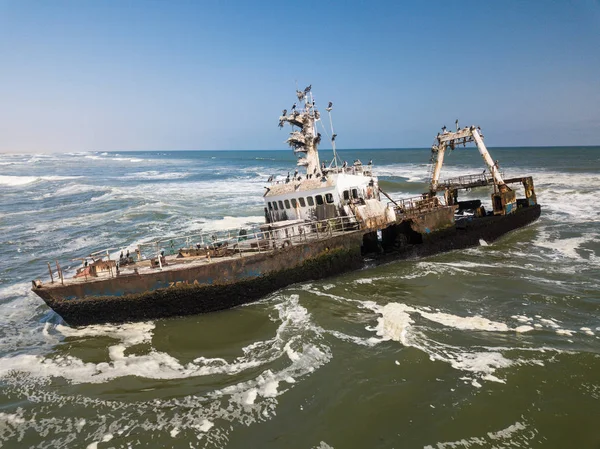 Abandonado e abandonado velho naufrágio Zeila na costa atlântica perto de Swakopmund e famosa costa esquelética na Namíbia, África. Grupo de pássaros corvos-marinhos empoleirados em navio enferrujado. Vista para drones . — Fotografia de Stock