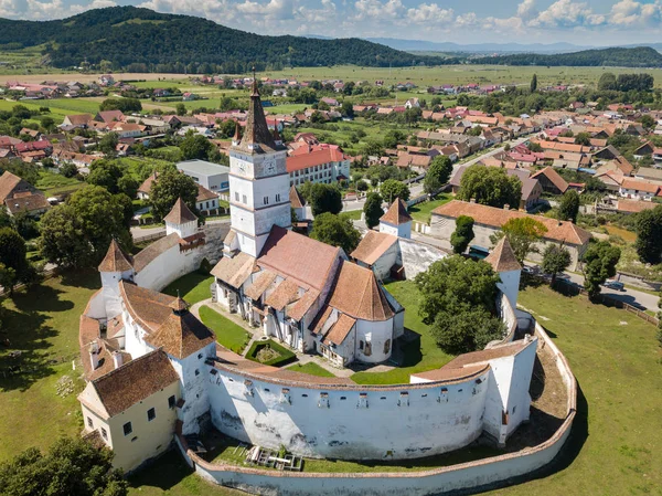 Veduta aerea della chiesa fortificata circondato da potenti mura spesse in Transilvania si affaccia sul villaggio in una bella giornata estiva. Romania . — Foto Stock