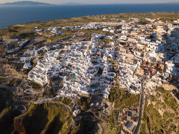 Vista aérea da ilha de Santorini, Grécia, aldeia de Oia com moinhos de vento e casas brancas. Vista incrível do pôr do sol da ilha romântica de quadcopter.The lugar mais romântico para um casamento . — Fotografia de Stock