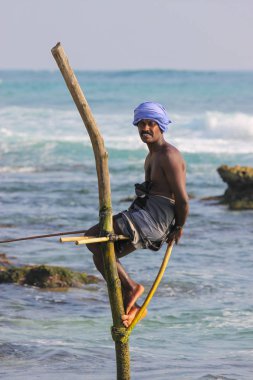 Ahangama, Sri Lanka-03 Ocak 2012: Yerel balıkçılar eşsiz bir geleneksel yöntemle avlanıyor. Tek bir kereste direğinde ya da çubuğunda duran. Sadece bu Hint okyanusunda bulunabilir..