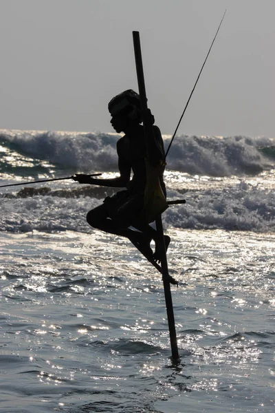 АХАНГАМА, ШРИ-ЛАНД-03 ЯНВАРЯ 2012 года: Местные рыбаки ловят рыбу в уникальном традиционном стиле. Стоять на единственном деревянном столбе или столбе можно только в этом Индийском океане . — стоковое фото