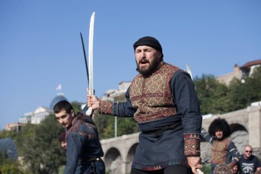 Gürcistan, Tiflis-07 Ekim 2017: Gürcü milli kostümlü savaşçılar bıçak, kılıç ve kalkan taşıyor ve Tiflis bayramında savaşıyorlar. Ekim festivali