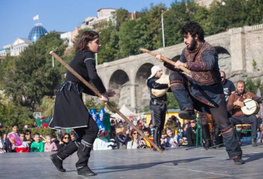 Gürcistan, Tiflis-07 Ekim 2017: Gürcü milli kostümlü savaşçılar bıçak, kılıç ve kalkan taşıyor ve Tiflis bayramında savaşıyorlar. Ekim festivali