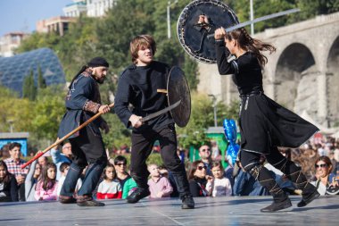 Gürcistan, Tiflis-07 Ekim 2017: Gürcü milli kostümlü savaşçılar bıçak, kılıç ve kalkan taşıyor ve Tiflis bayramında savaşıyorlar. Ekim festivali