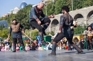 Gürcistan, Tiflis-07 Ekim 2017: Gürcü milli kostümlü savaşçılar bıçak, kılıç ve kalkan taşıyor ve Tiflis bayramında savaşıyorlar. Ekim festivali