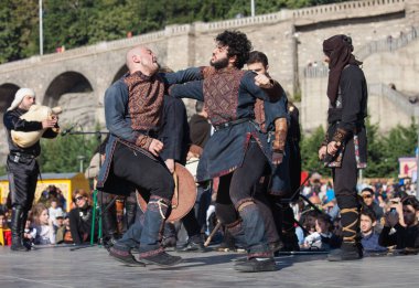 Gürcistan, Tiflis-07 Ekim 2017: Gürcü milli kostümlü savaşçılar bıçak, kılıç ve kalkan taşıyor ve Tiflis bayramında savaşıyorlar. Ekim festivali