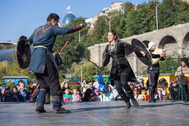 Gürcistan, Tiflis-07 Ekim 2017: Gürcü milli kostümlü savaşçılar bıçak, kılıç ve kalkan taşıyor ve Tiflis bayramında savaşıyorlar. Ekim festivali