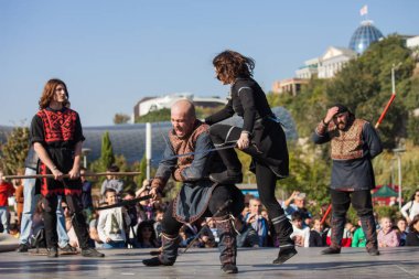 Gürcistan, Tiflis-07 Ekim 2017: Gürcü milli kostümlü savaşçılar bıçak, kılıç ve kalkan taşıyor ve Tiflis bayramında savaşıyorlar. Ekim festivali