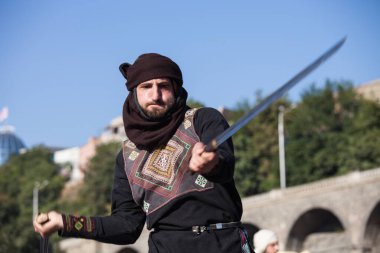 Gürcistan, Tiflis-07 Ekim 2017: Gürcü milli kostümlü savaşçılar bıçak, kılıç ve kalkan taşıyor ve Tiflis bayramında savaşıyorlar. Ekim festivali