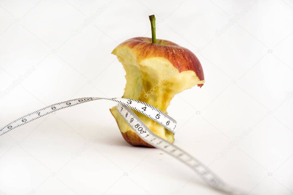 Apple eaten with meter around on white background expresses the concept of anorexia