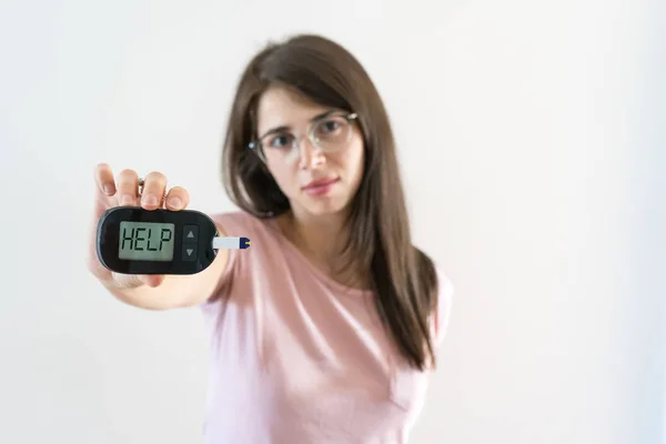 Девочка с сахарным диабетом показывает глюкометр и просит о помощи — стоковое фото