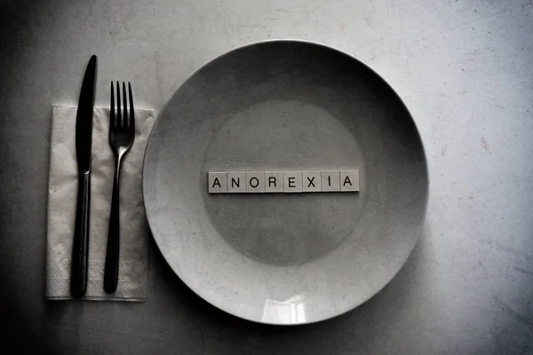 Порожня тарілка з анорексією, написаною всередині великих літер. Чорно-білий в гранжевому стилі — стокове фото