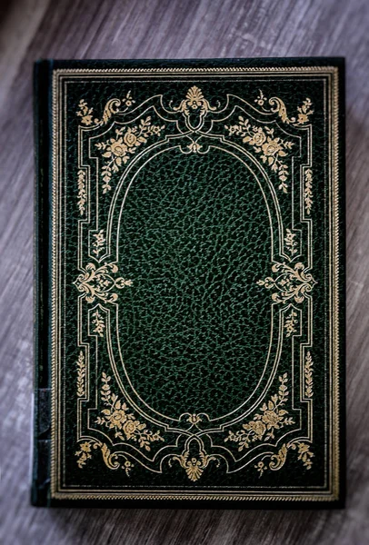 Libro antiguo con cubierta verde con decoraciones doradas apoyadas en la mesa de madera — Foto de Stock