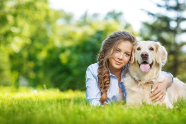Golden Retriever köpeğiyle yaz parkında genç bir kadın.