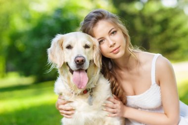 Golden Retriever köpeğiyle yaz parkında genç bir kadın.