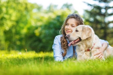 Golden Retriever köpeğiyle yaz parkında genç bir kadın.
