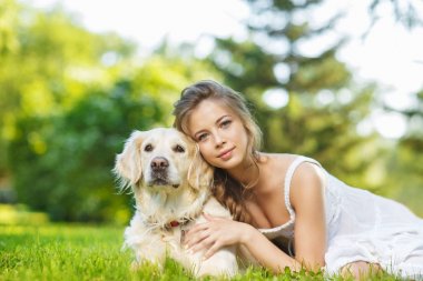 Golden Retriever köpeğiyle yaz parkında genç bir kadın.