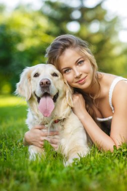 Golden Retriever köpeğiyle yaz parkında genç bir kadın.