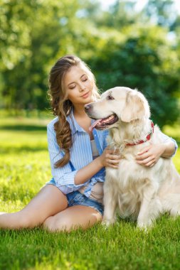 Golden Retriever köpeğiyle yaz parkında genç bir kadın.