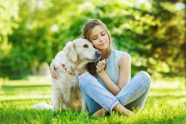 Golden Retriever köpeğiyle yaz parkında genç bir kadın.