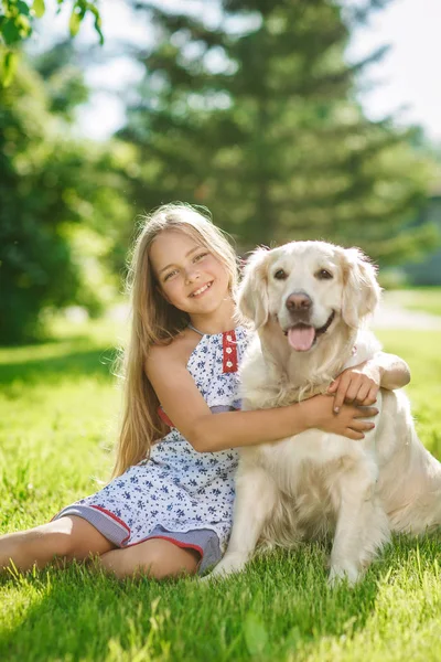 Little girl with golden retriever dog in the park