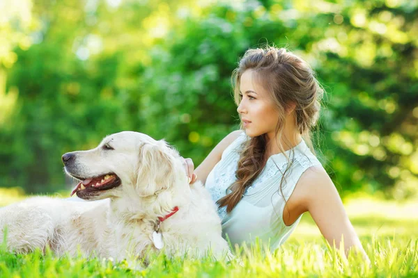 Golden Retriever köpeğiyle yaz parkında genç bir kadın.