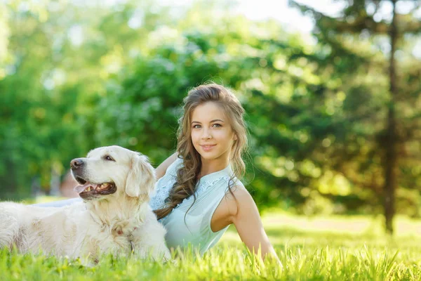 Golden Retriever köpeğiyle yaz parkında genç bir kadın.