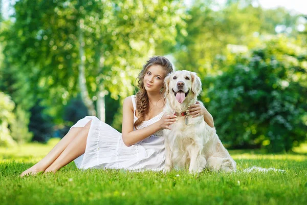 Golden Retriever köpeğiyle yaz parkında genç bir kadın.