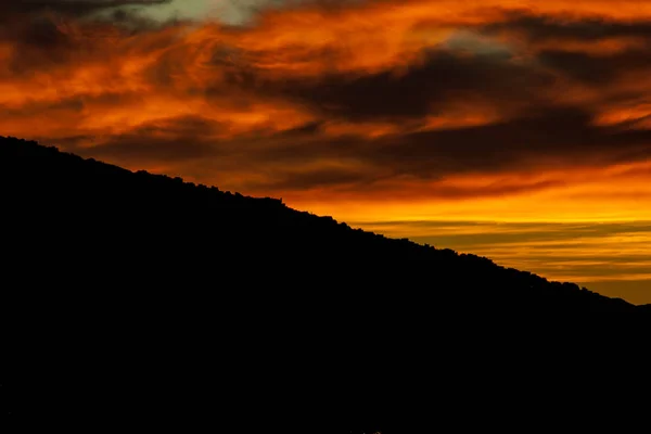 Сенсационный закат за горой с облачными образованиями — стоковое фото