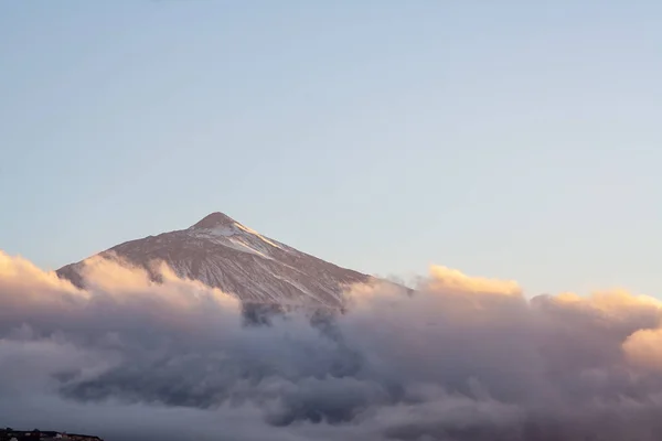 Montaña nevada al atardecer con nubes envueltas —  Fotos de Stock
