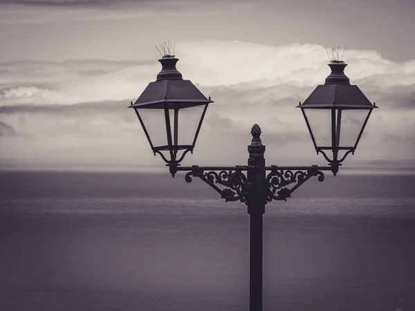 Stylistic street lanterns with sea and clouds in the background — Stock Photo, Image