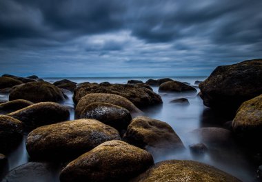 gökyüzünde fantastik Bulutlar ile bir kaya plajı üzerinde yaratıcı uzun süreli fotoğraf