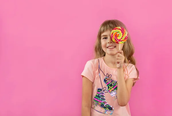 Uma Menina Está Olhando Através Chupa Chupa Menina Fundo Rosa — Fotografia de Stock