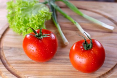 Ahşap zemin üzerinde salata ve soğan ile sulu kırmızı domatesler. Vejetaryen yemeği. Olgun domatesler, bir damla suyla..