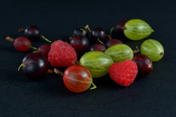 Assorted berries on a black background. Juicy wild berries.