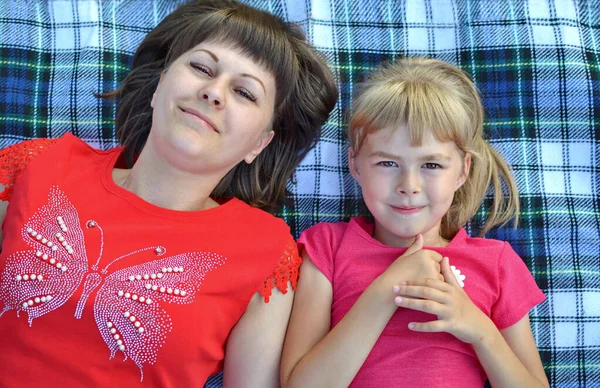 少女は母親と遊ぶ絨毯の上に横たわっている ベッドの広がりを確認しました 少女と母親は嘘をついて笑っている ピンクのTシャツを着た女の子 少女と母親 陽気な赤ん坊 — ストック写真