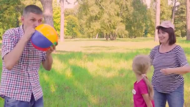 Père pour fille gonfle le ballon. Vacances en famille dans le parc dans la nature. Père et fille s'amusent. Jour de famille. Grand-mère et petite-fille marchent dans le parc. — Video