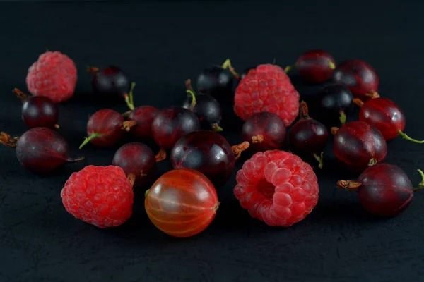 Assorted berries on a black background. Juicy wild berries.